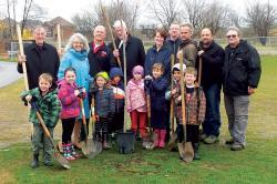 group of kids and adults posing after tree planting on arbor day