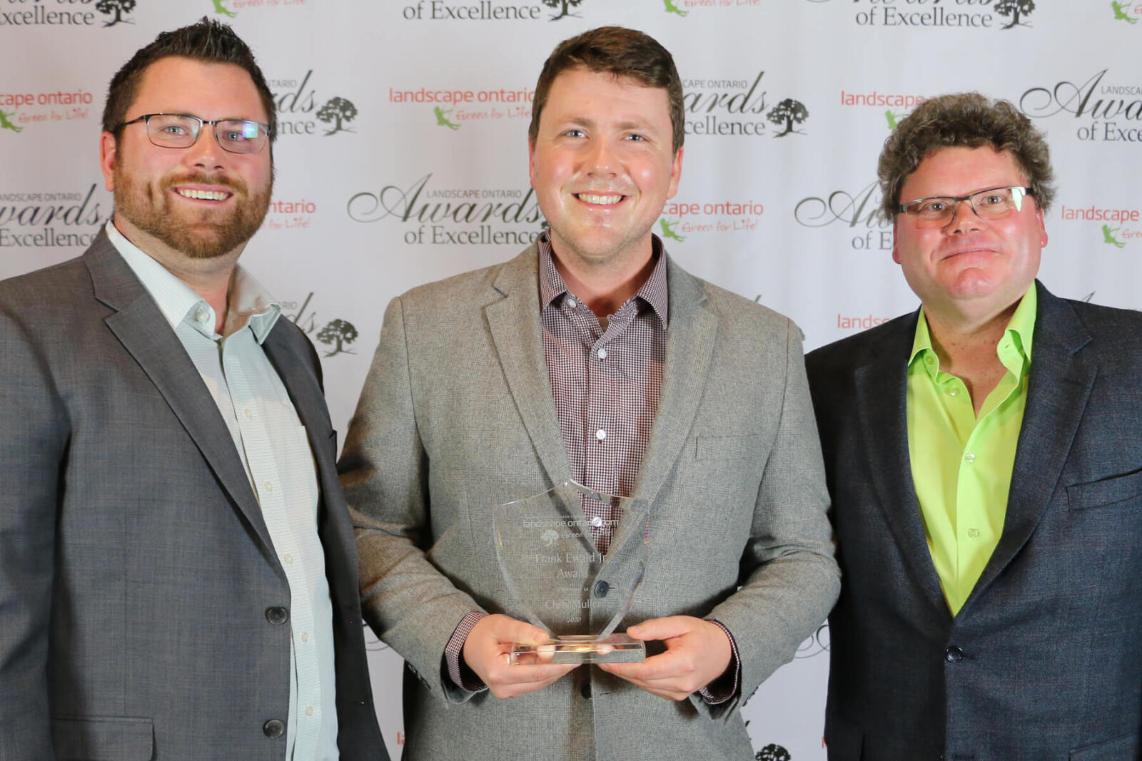 three men. one holding an award