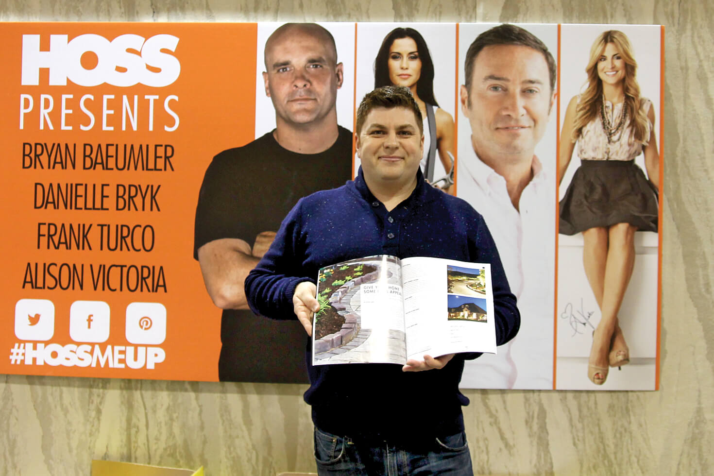 man holding magazine in front of a poster