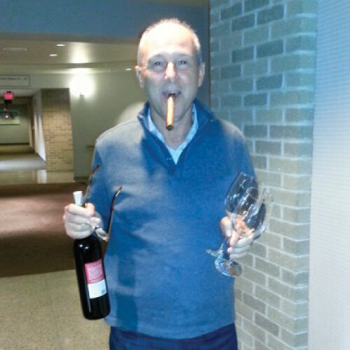 man holding bottle of wine and glasses