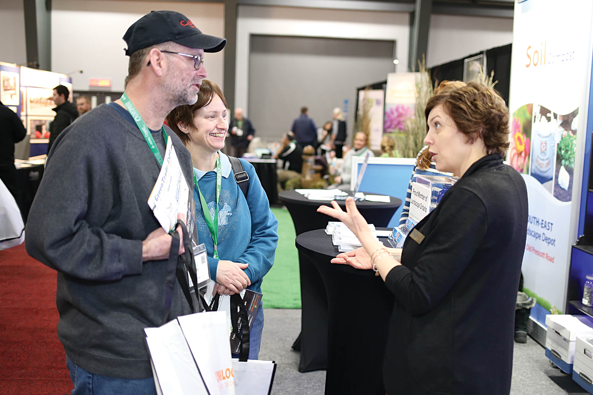 man and woman talking with an exhibitor at a trade sho