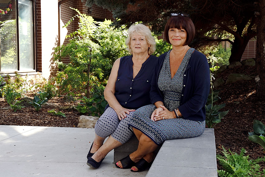 two women sitting in front of a garden