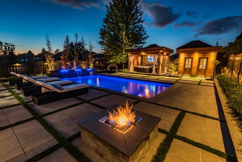 2016 - Landscape Lighting Design & Installation - $10,000 - $30,000 - This night shot captures the LED lights from the pool and the vibrant pot lights from the two accessory structures. Down lighting fixtures could also be found highlighting the fence that was painted black. Pot lights were also installed high up inside the tree that is located in the background.