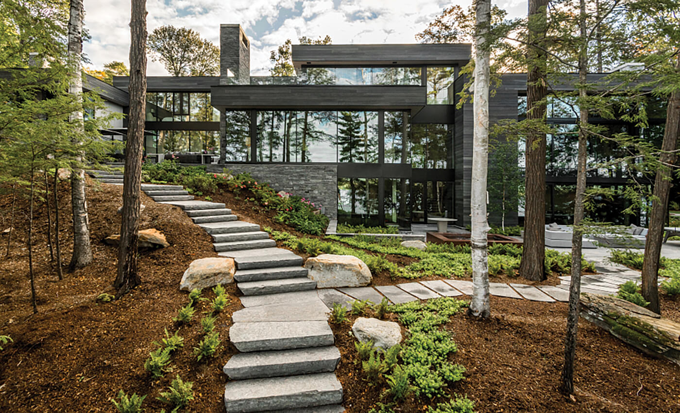 A modern looking house in the woods with converging natural stone steps