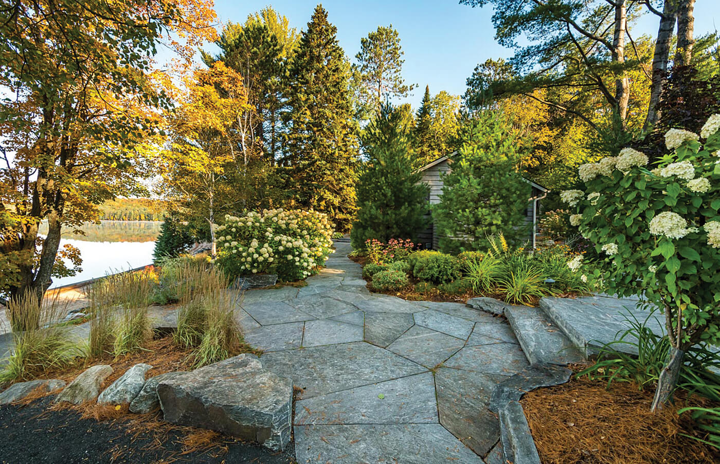 A large natural stone patio surrounded by plants and trees