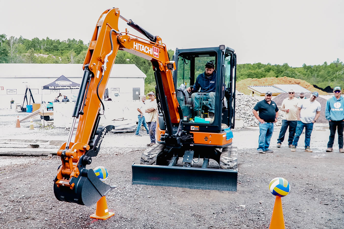 A person using an excavator to place a volleyball on a pylon