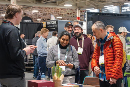 People talking with an exhibitor at a busy trade show