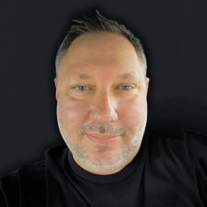 Headshot of a man in a black shirt on a black background