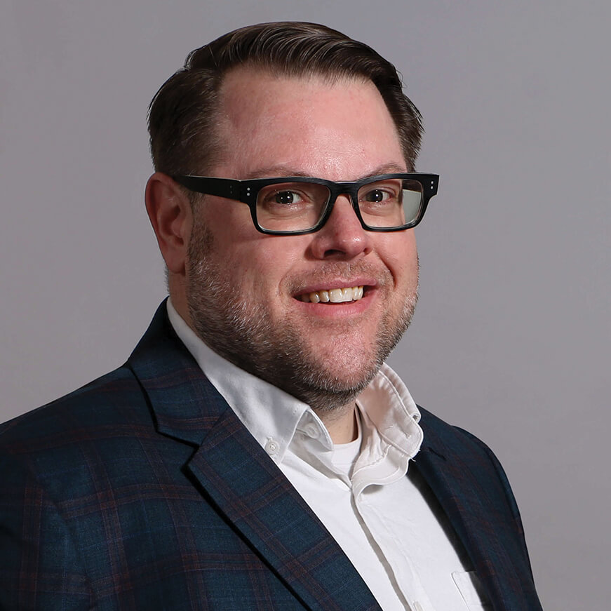 A man in a suit jacket and white shirt with glasses