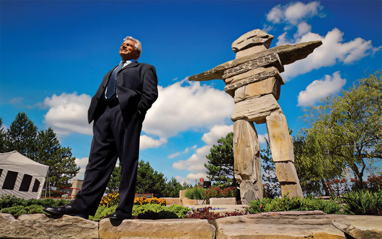 a man standing in front of a giant stone inukshuk