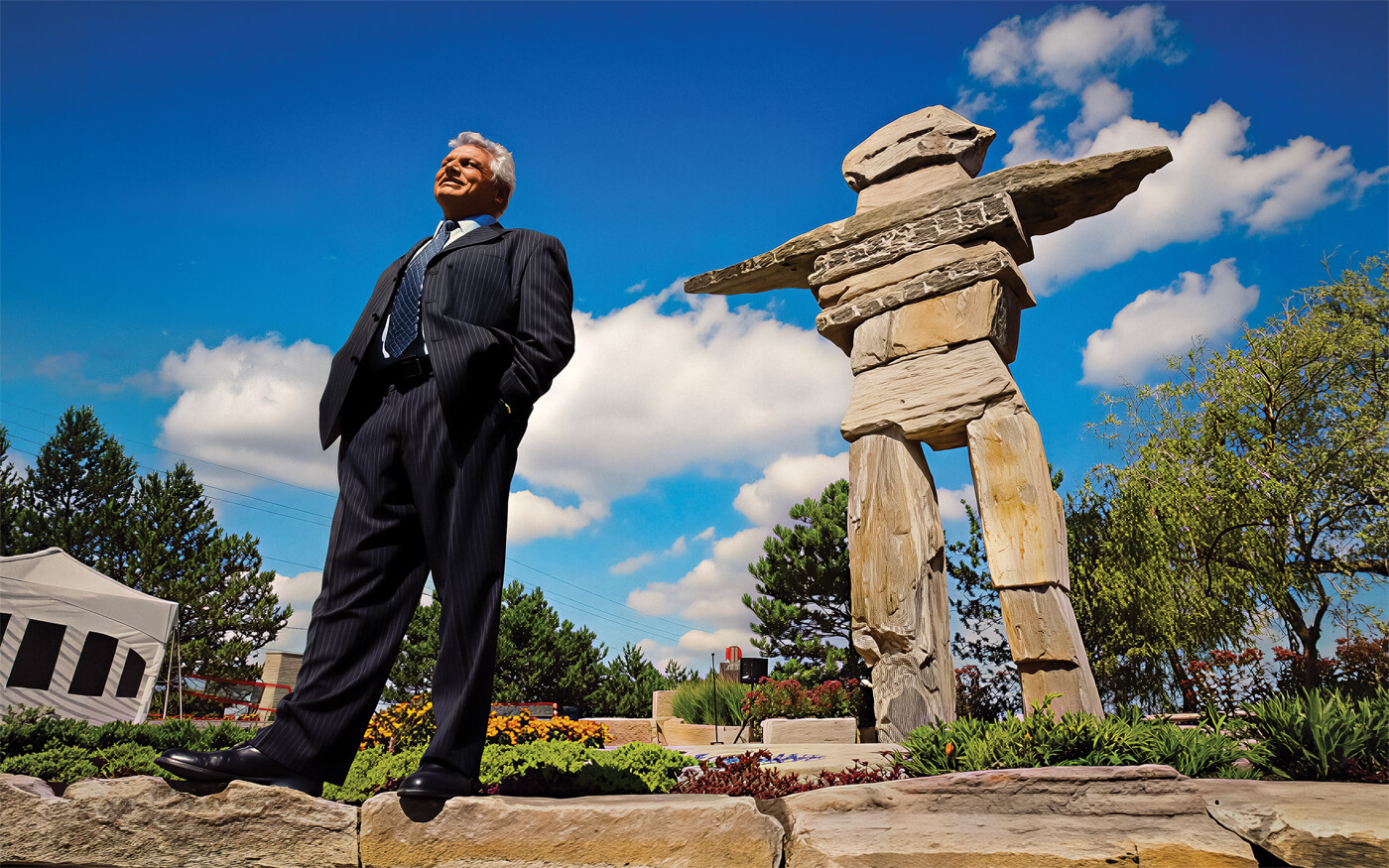 a man standing in front of a giant stone inukshuk