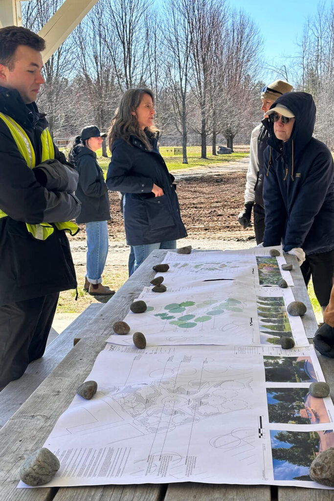 People standing around a paper plan inside a gazebo